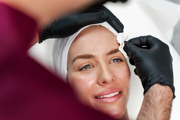 Attractive woman is getting a rejuvenating facial injections at beauty clinic. The expert...