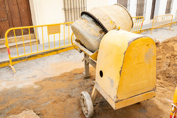 reconstruction work on a city street - a yellow concrete mixer on a construction site