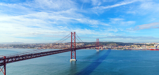 panoramic photo of the cityscape of Lisbon and the 25 April red bridge over the Tagus river on a sunny autumn day
