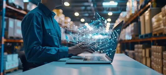 Logistics manager monitoring automated warehouse operations using a laptop. 