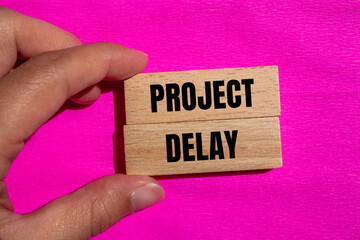 Project delay words written on wooden blocks with pink background. Conceptual project delay symbol....