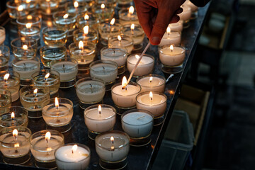 Girl's hand lights candles in church for a prayer. Photos of tranquility and religion. Calm places of peace for people