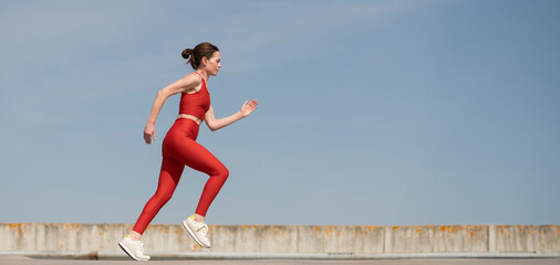 mid adult woman running and jogging outside, blue sky background