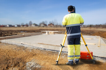 Builder surveyor. Engineer conducts geodetic surveys. Surveyor guy near foundation of house....