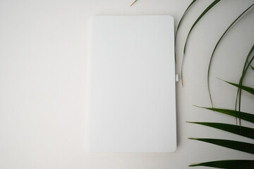 
White book on a background of palm leaves. Book mockup.