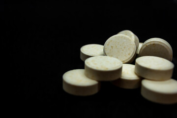 Pills on a black background. Focus on foreground, soft bokeh.