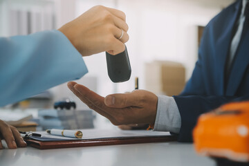 Insurance officers hand over the car keys after the tenant. have signed an auto insurance document...