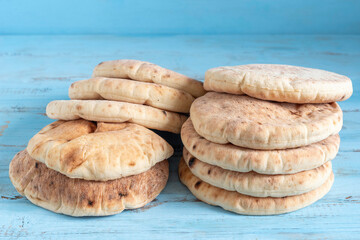 Freshly baked pita bread or flatbread on blue wooden background.