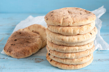 Freshly baked pita bread or flatbread on blue wooden background.	