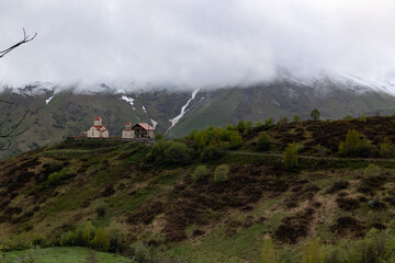 Gudauri, Georgia in cloudy weather with green grass and snow on montains pics in May. View on ...
