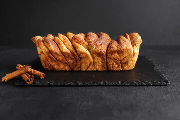 Homemade sweet yeast pastry cinnamon sliced bread sliced on black board. copy space