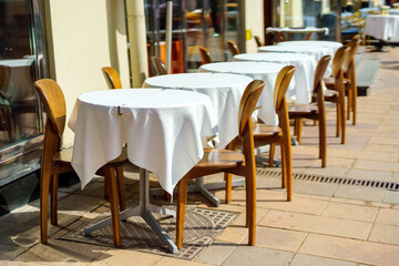 Row of square tables with white tablecloths at an outdoor restaurant