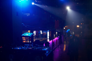 Close-up of a remote DJ with vinyl discs in a nightclub with a beautiful background blur.
