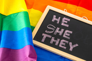 HE SHE THEM Handwritten in chalk on a school blackboard, concept on the background of a rainbow...
