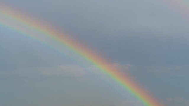 Time-lapse of clouds and a double rainbow after the rain on a blue sky.