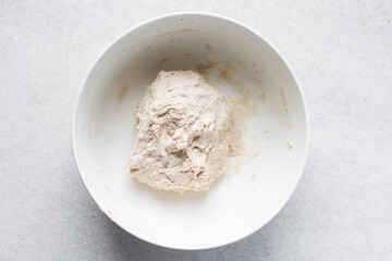 Overhead view of roughly mixed bread dough, flatlay of high hydration bread dough in a white bowl