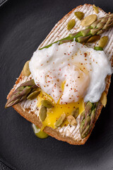 Delicious hearty breakfast consisting of poached eggs on toast with cream cheese, asparagus