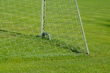 corner of soccer goal with net from behind on green soccer field grass