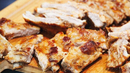 A close up of a piece of meat with a knife on a wooden cutting board. The meat is cut into small pieces and he is raw