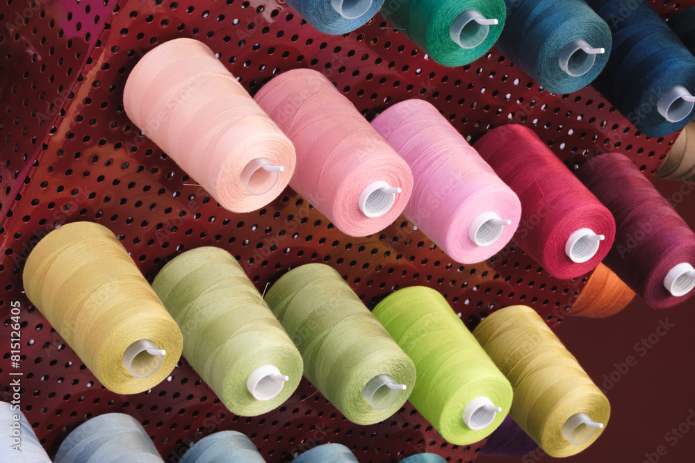 Aufkleber a rack of colorful spools of thread. the spools are arranged in a row, with some being green, pink, 
