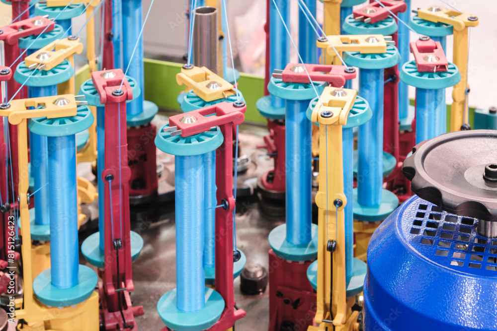 Aufkleber a machine with many colorful parts is spinning yarn. the machine is blue and yellow. the yarn is bei