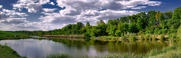 Recreational area. Fishing grounds. Pond and recreation area.Spring clouds along the pond.
