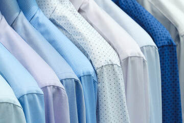 A row of shirts with different colors and patterns hanging on a clothesline. The shirts are neatly...