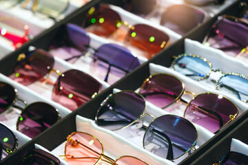 A row of sunglasses with different colors and styles. The sunglasses are displayed in a case, and...