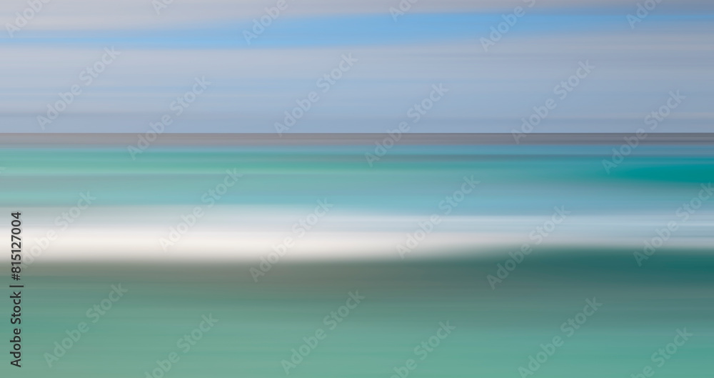 Aufkleber a blurry image of a beach with a blue ocean and white sand. the image has a dreamy, ethereal quality