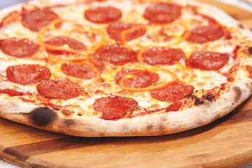 A pepperoni pizza with a few slices missing. The pizza is on a wooden board. The pizza is very large and has a lot of pepperoni on it