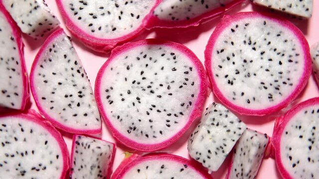 Slices of fresh white pitaya or dragon fruit on pink background, flat lay. Concept of exotic tropical and vegan  food. 360 degrees rotation