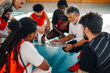 Elderly male coach discussing game tactics with his diverse basketball team
