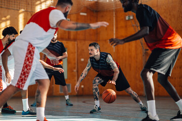 Naklejka premium Tattooed hispanic basketball player dribbling the ball while playing the game