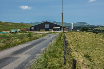 farm with barns, silos and antenna at asphalt road in the French landscape of the Auvergne with...