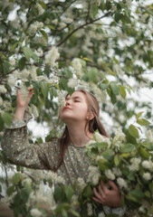 A photo of a beautiful girl near a flowering tree.