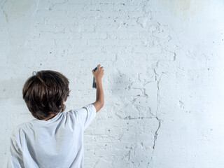 A boy is painting a wall with a spray can