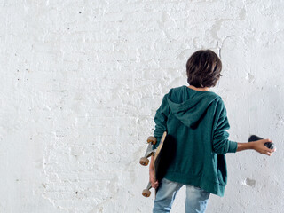 A boy is holding a skateboard and a spray paint for graffiti