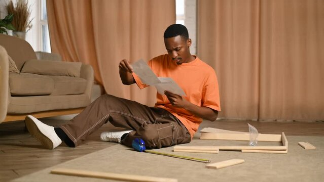 Young black man assembling a rack according to instructions at home
