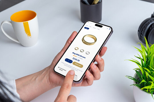 Woman using smartphone to shop for zircon ring online. Convenience meets elegance as she browses jewelry on ecommerce store