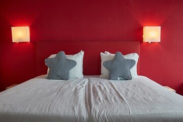 Hotel bed with white sheets, red wall