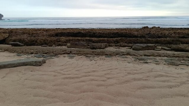 Landscape view of sea sand, moss and coral rocks on a cloudy summer day. Molang Beach, Tulungagung, Indonesia
