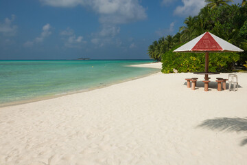 Tropical beach with palm trees, umbrella and table for relaxing moments