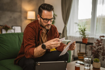 Adult caucasian man sit on sofa and read recipe for medical at home