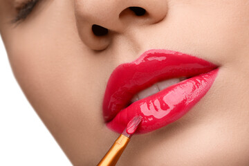Woman applying lip gloss on white background, closeup