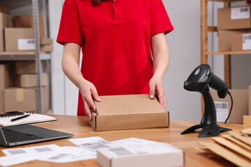 Post office worker packing parcel at wooden table indoors, closeup
