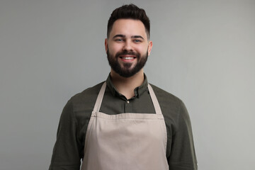 Smiling man in kitchen apron on grey background. Mockup for design