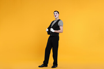 Mime artist making shocked face on orange background