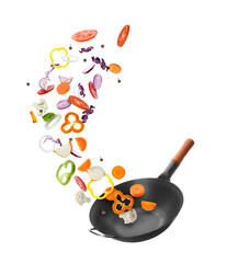 Frying pan and different vegetables in air on white background