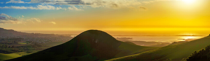 Panorama of silhouetted hill and ocean at sunset sunrise