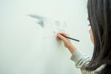 Unrecognizable little girl performs mathematical calculations on the wall